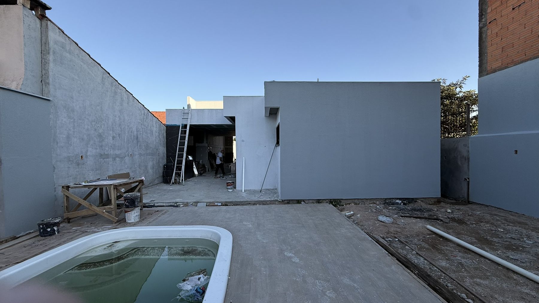 Fachada de volumes brancos e cinzas com piscina em primeiro plano